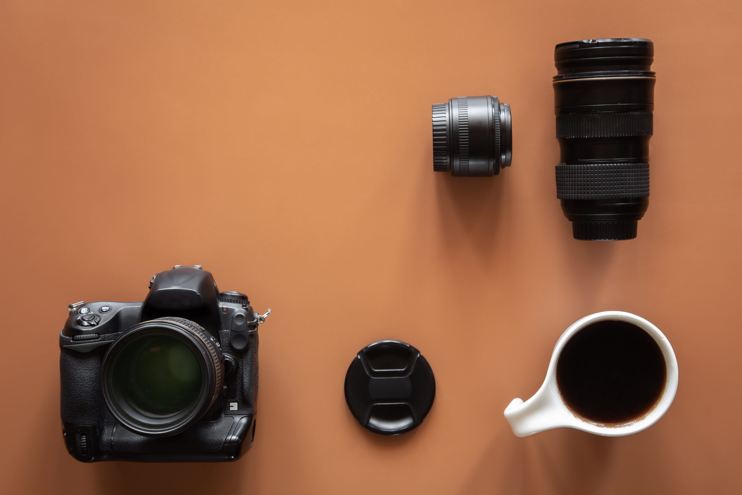 Photographer’s workplace with camera and lens, flat lay.